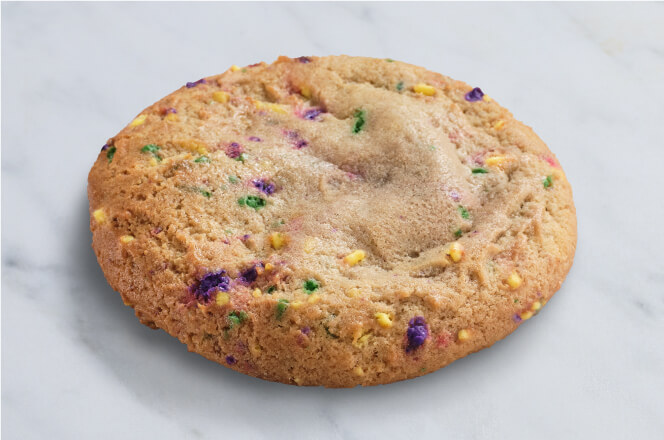 A cinnamon flavored, mardi gras-themed cookie decorated with colorful sprinkles and filled with cream cheese.